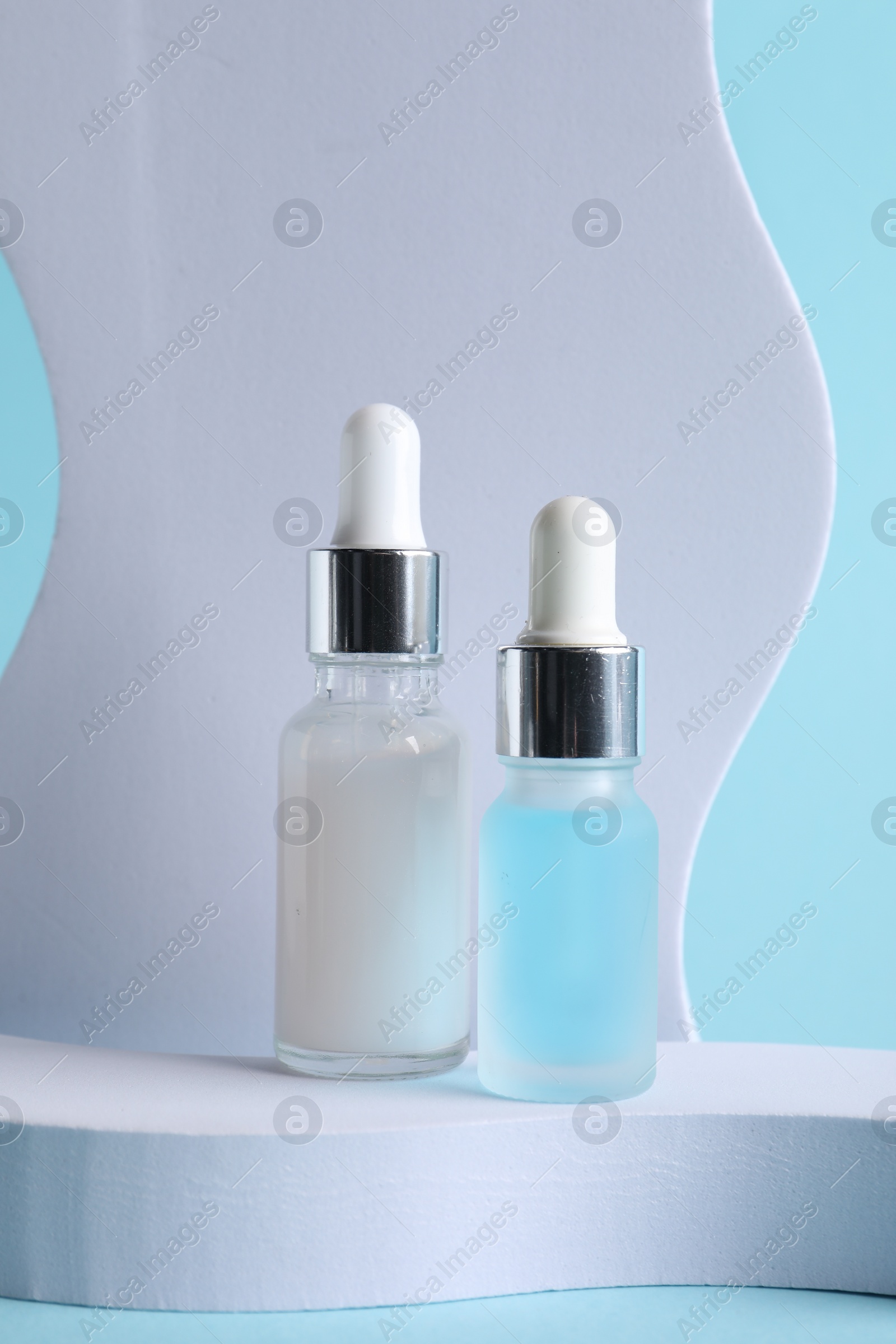 Photo of Stylish presentation of cosmetic serum on light blue background