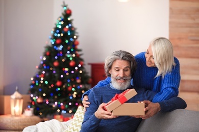 Happy couple opening Christmas gift at home