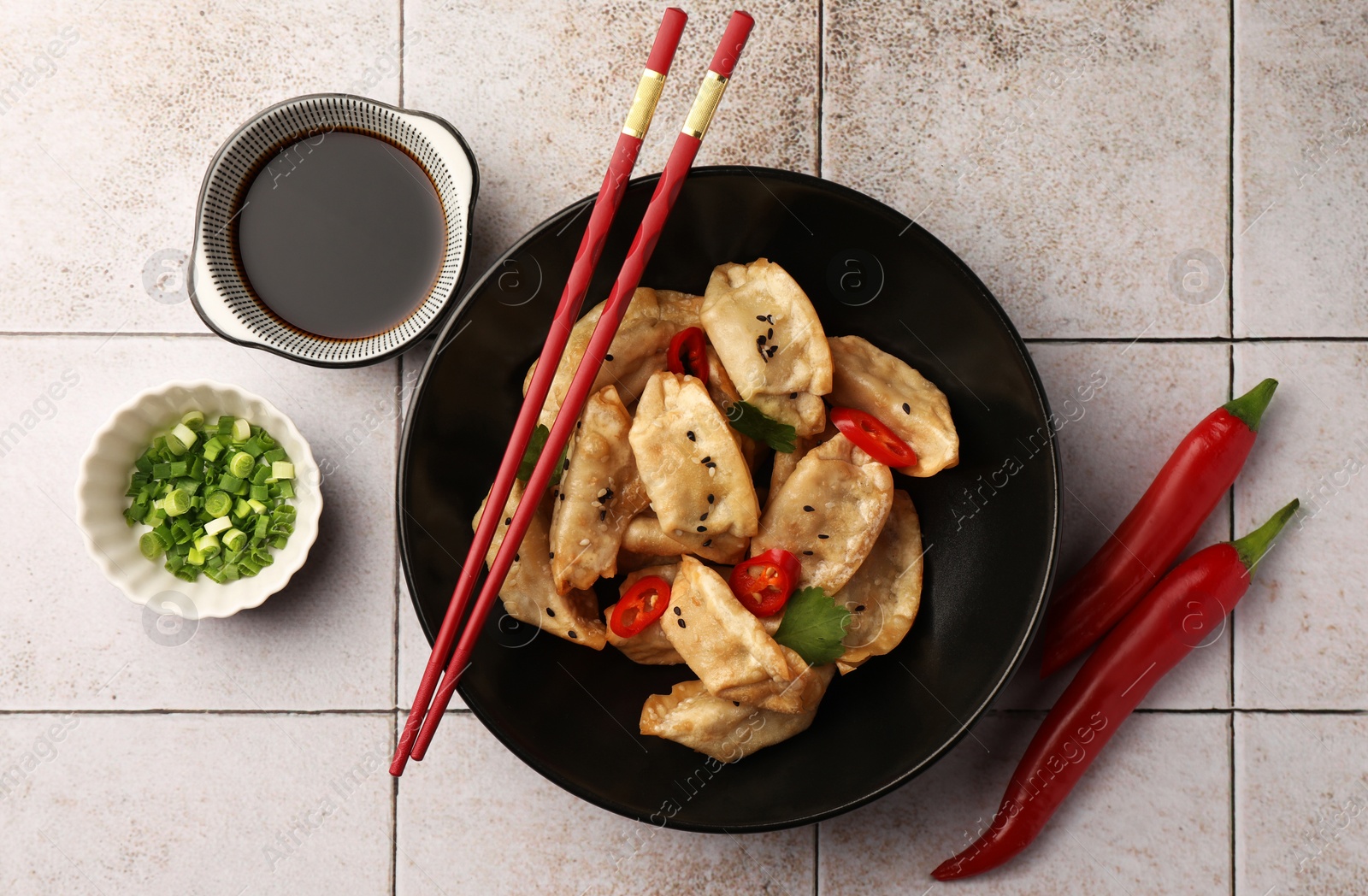 Photo of Delicious gyoza (asian dumplings) served on light tiled table, flat lay