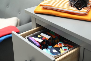 Chest of drawers with different folded clothes and belt indoors, closeup