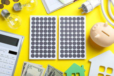 Photo of Flat lay composition with solar panels and piggy bank on yellow background