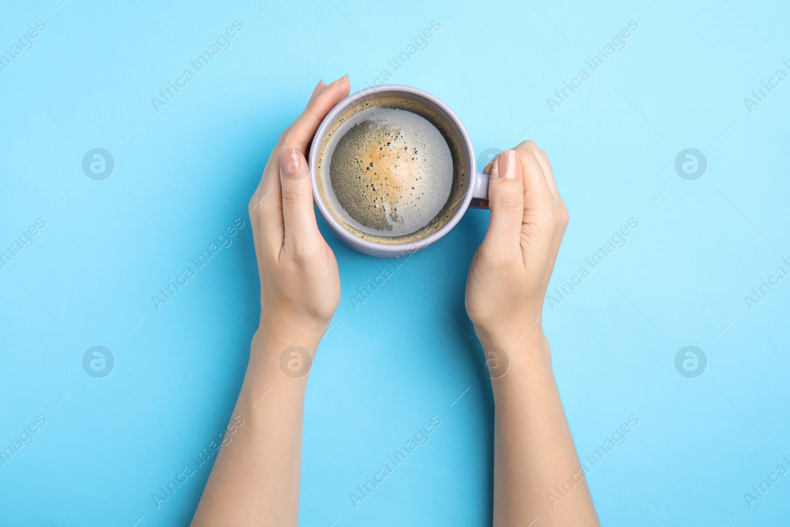 Photo of Woman with cup of coffee on light blue background, top view