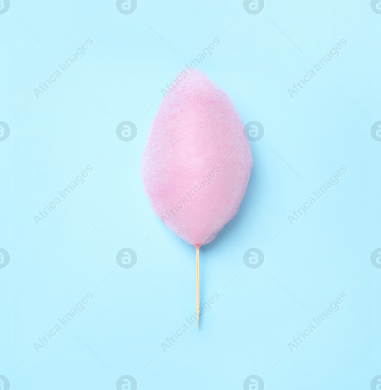Photo of Sweet pink cotton candy on light blue background, top view