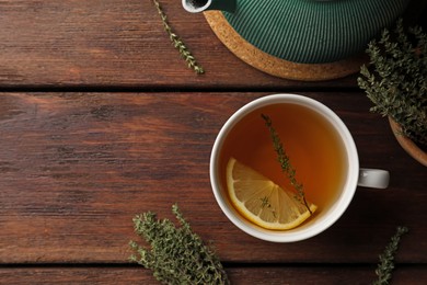 Aromatic herbal tea with thyme and lemon on wooden table, flat lay. Space for text