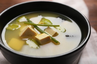 Photo of Bowl of delicious miso soup with tofu on table, closeup