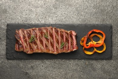 Photo of Delicious grilled beef steak with spices on gray table, top view