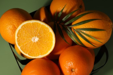 Photo of Fresh oranges in metal basket on green background, top view