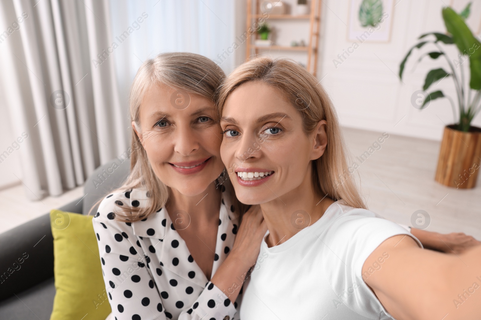 Photo of Happy daughter taking selfie with her mature mother at home