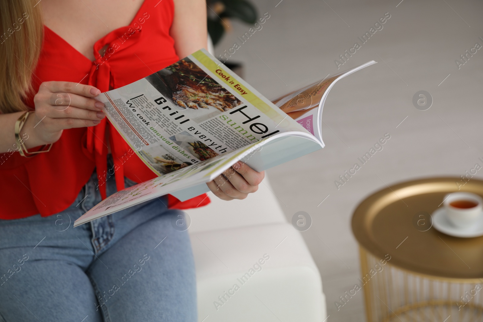 Photo of Woman reading magazine on sofa indoors, closeup