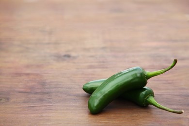 Photo of Fresh ripe green jalapeno peppers on wooden table. Space for text