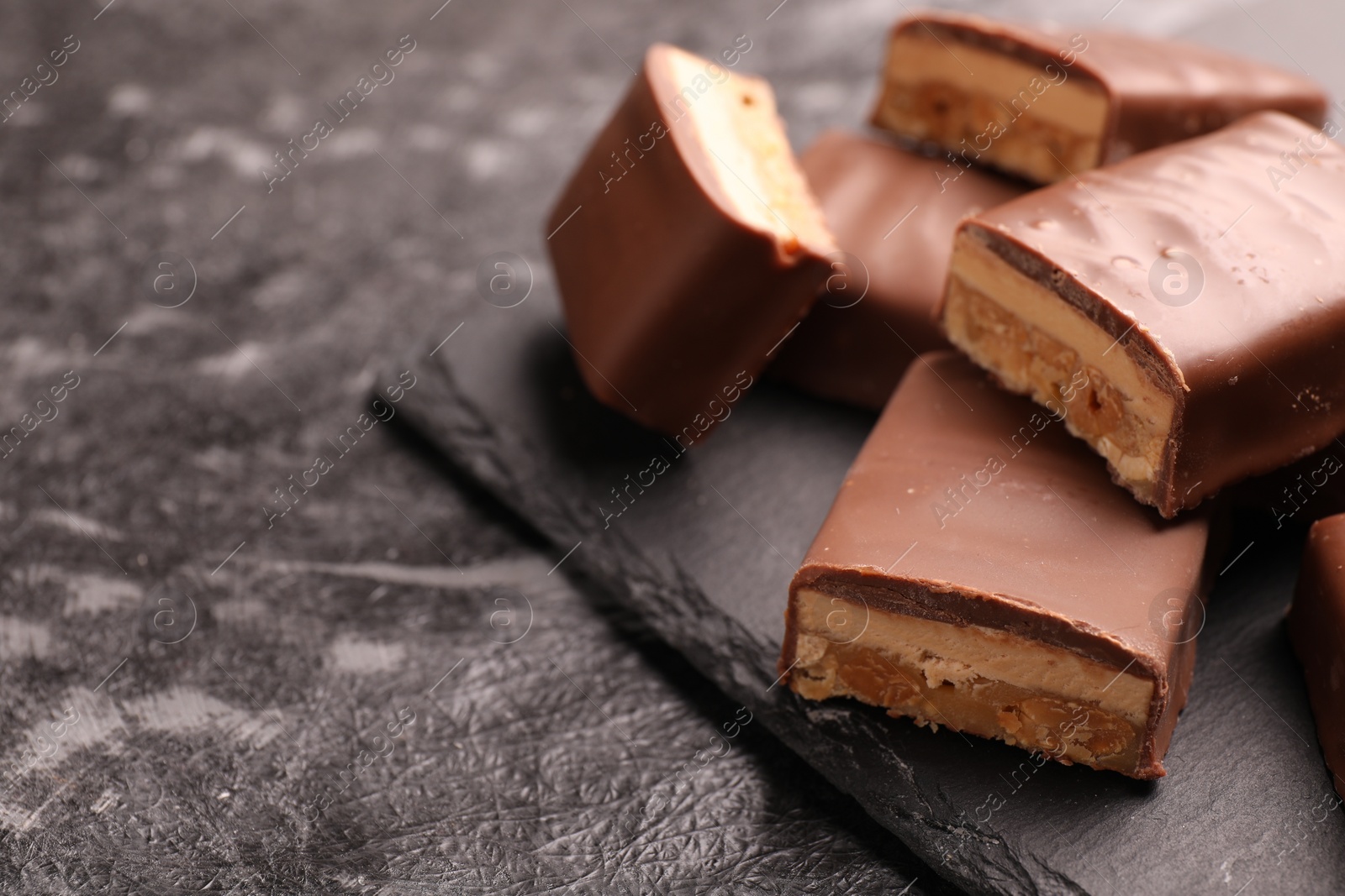 Photo of Tasty chocolate bars with nougat on gray table, closeup. Space for text