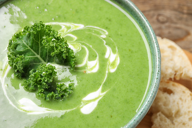 Photo of Tasty kale soup with cream on table, closeup