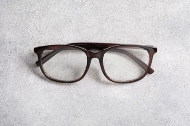Photo of Glasses in stylish frame on light grey background, above view