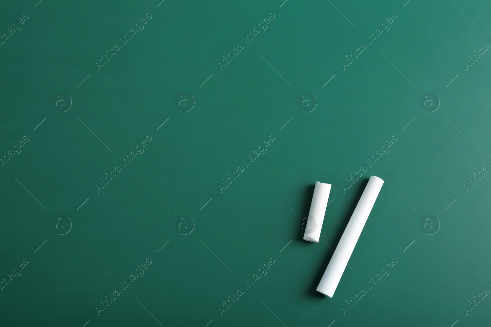 Photo of Pieces of chalk on green background, top view