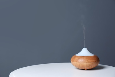 Photo of Aroma oil diffuser lamp on table against gray background. Space for text