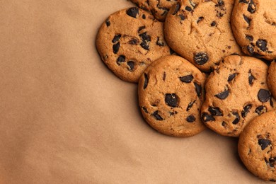 Photo of Delicious chocolate chip cookies on brown background, flat lay. Space for text