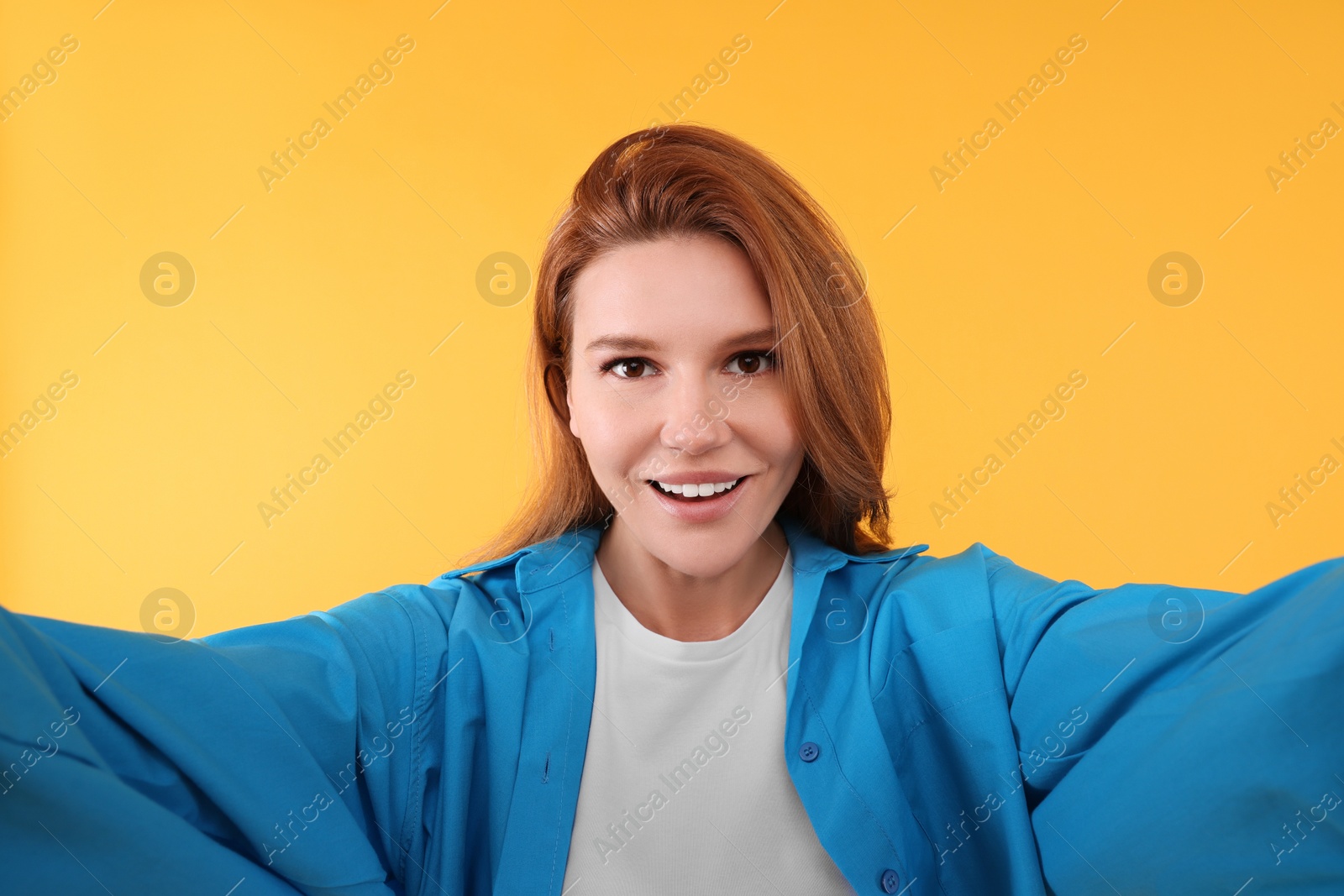 Photo of Beautiful woman taking selfie on orange background