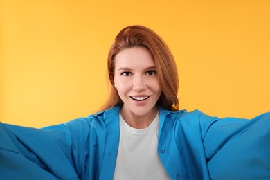 Beautiful woman taking selfie on orange background