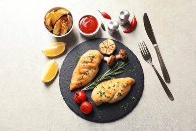 Photo of Fried chicken breasts served with sauce and garnish on grey background, flat lay