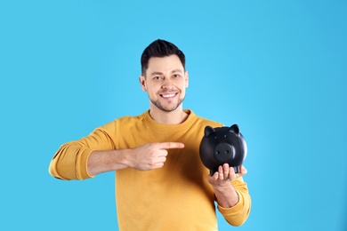 Man with piggy bank on color background