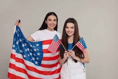 4th of July - Independence Day of USA. Happy woman and her daughter with American flags on light grey background