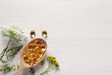 Spoon of pills and flowers on white wooden table, flat lay with space for text. Dietary supplements