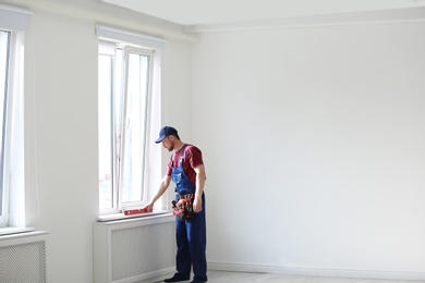 Photo of Handyman in uniform working with building level indoors, space for text. Professional construction tools