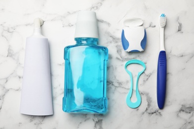 Flat lay composition with tongue cleaner and teeth care products on marble background