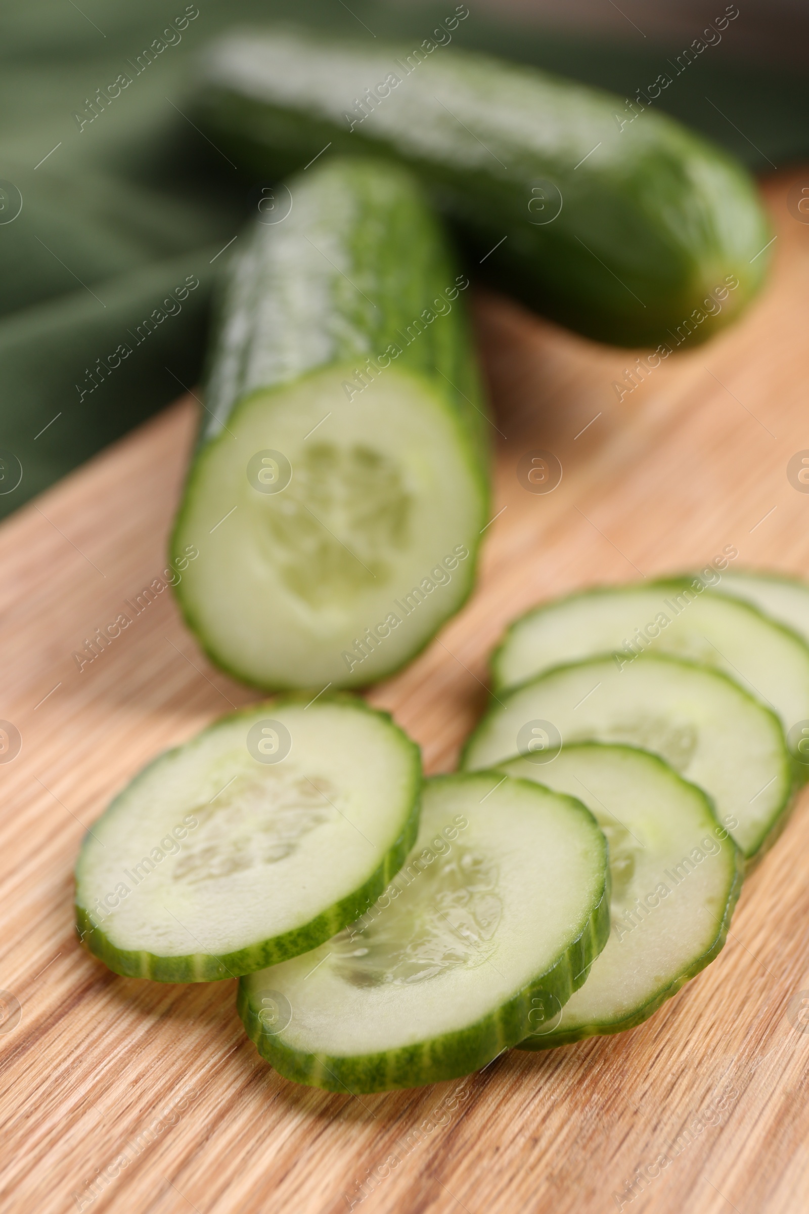 Photo of Cut ripe cucumber on wooden board, closeup