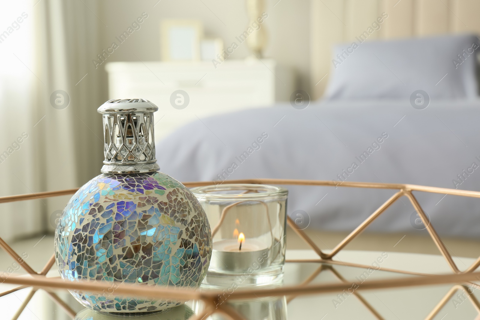 Photo of Closeup view of stylish catalytic lamp with burning candle on tray in bedroom, space for text. Cozy interior