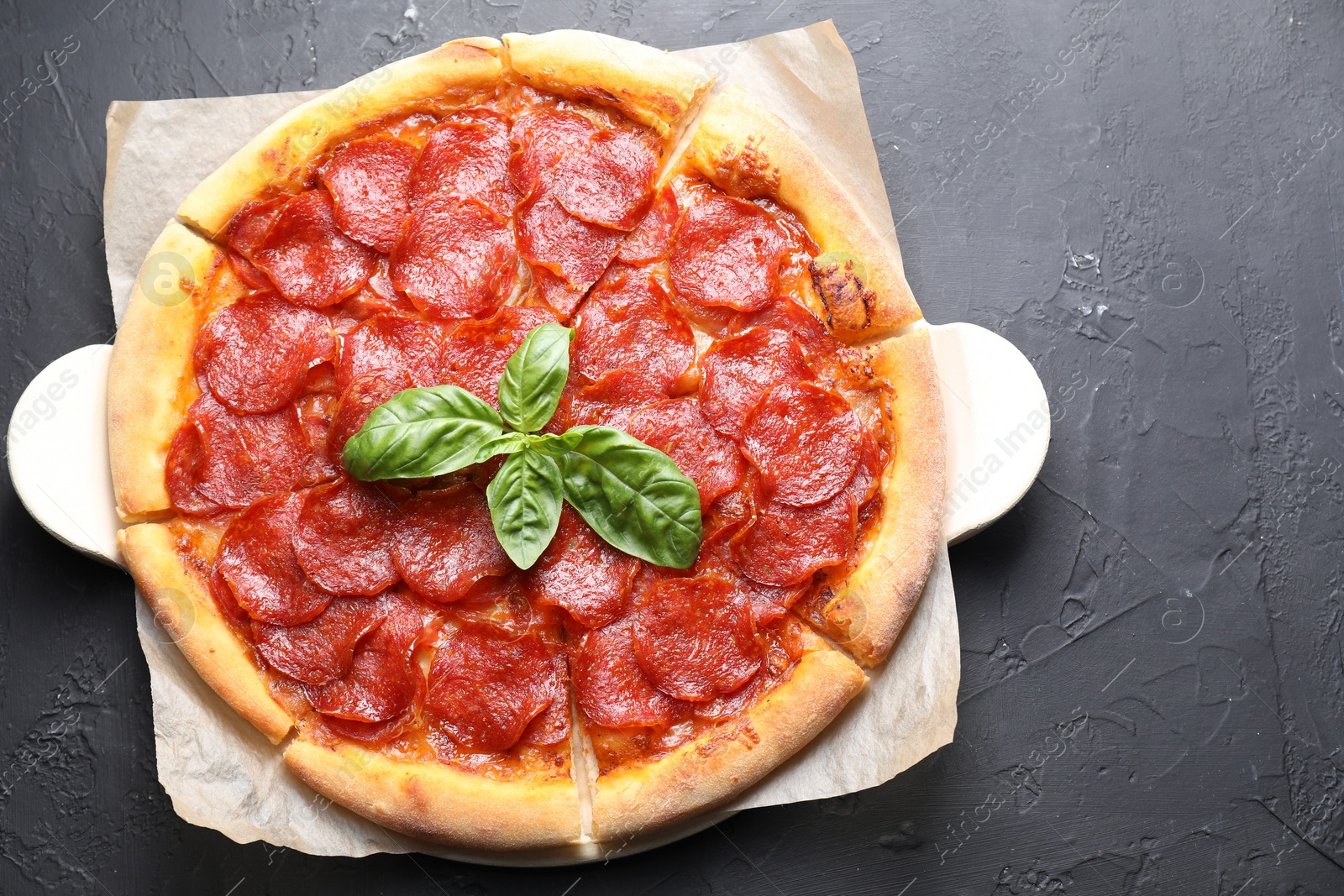 Photo of Tasty pepperoni pizza on black textured table, top view. Space for text