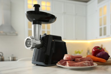 Photo of Modern meat grinder and products on white marble table in kitchen