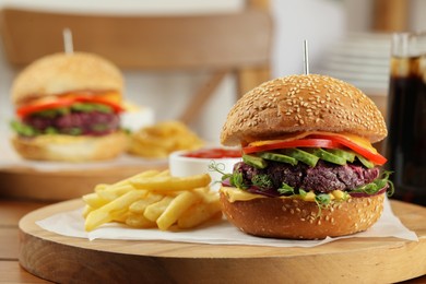 Photo of Tasty vegetarian burger served with french fries on wooden table, closeup. Space for text