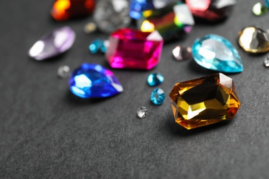 Photo of Different beautiful gemstones on black background. Space for text