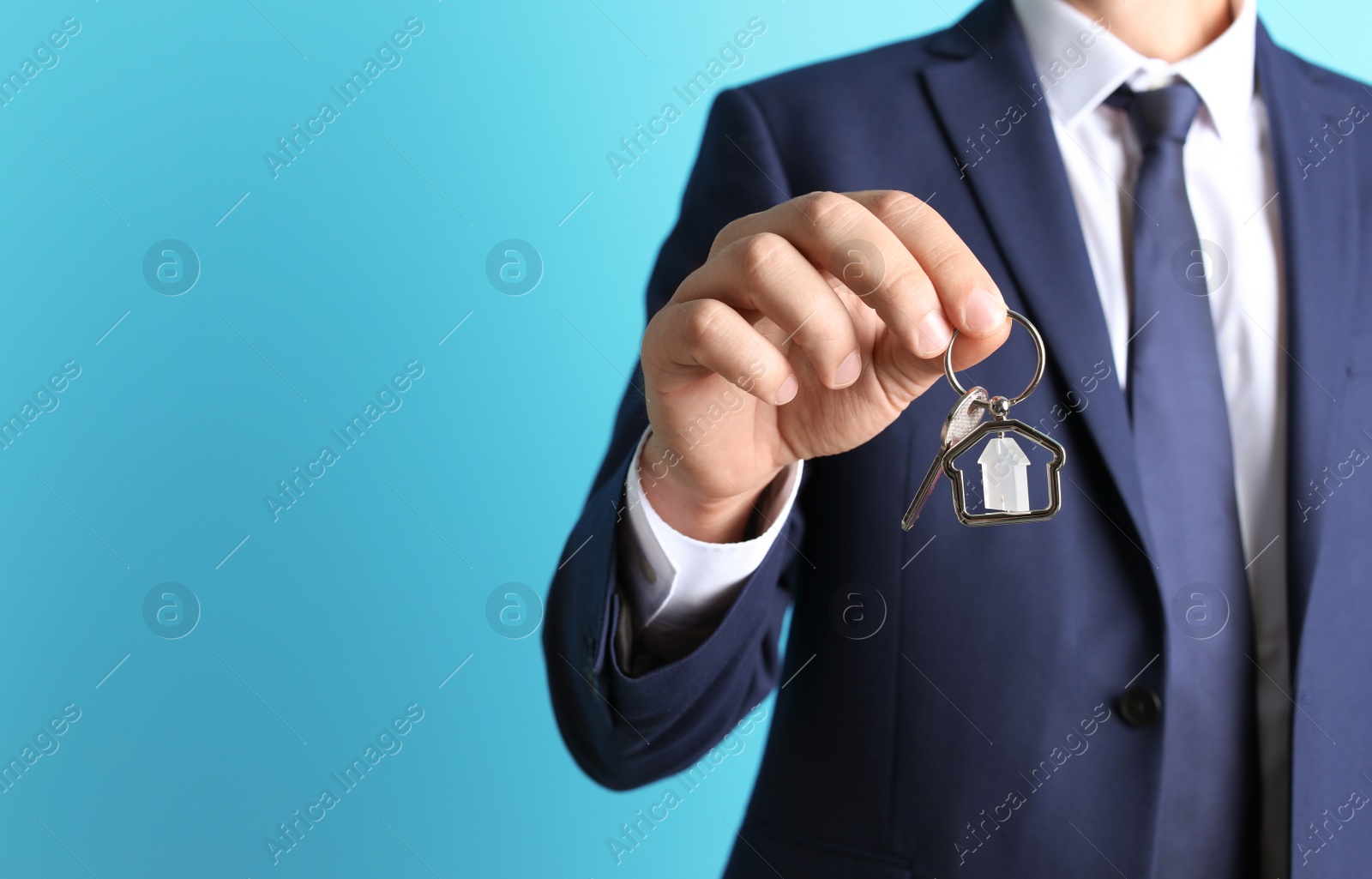Photo of Real estate agent holding key on color background, closeup
