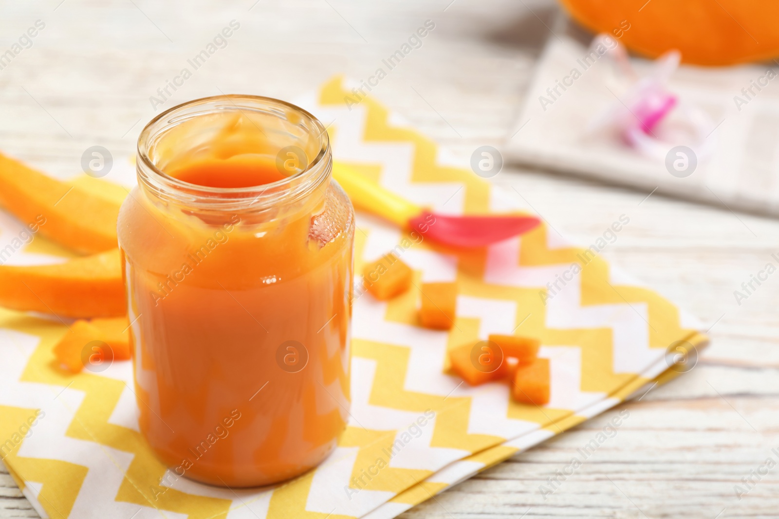 Photo of Jar with healthy baby food and cut pumpkin on table