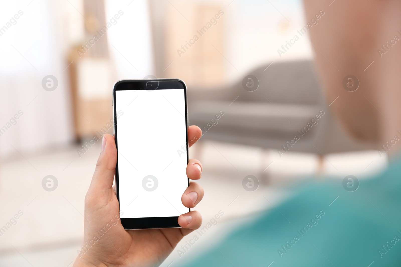 Photo of Man holding smartphone with blank screen indoors, closeup of hand. Space for text