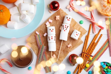 Image of Flat lay composition with funny snowmen made of marshmallows on white wooden table. Bokeh effect