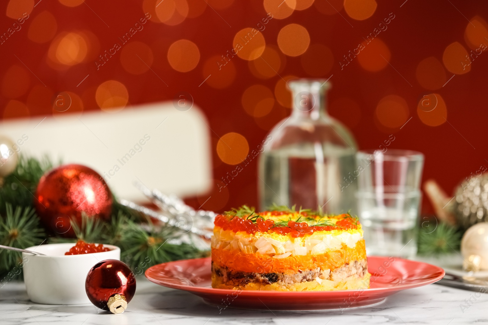 Photo of Traditional russian salad Mimosa and festive decor on table against blurred lights