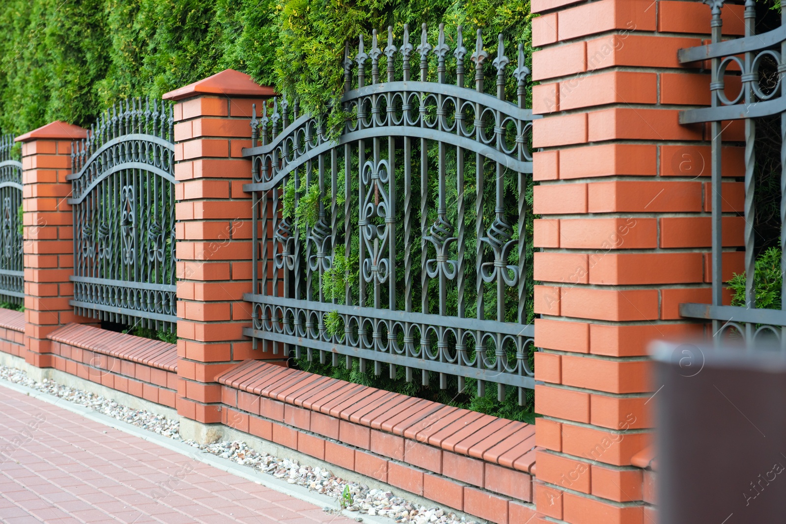 Photo of Beautiful brick fence with iron railing outdoors