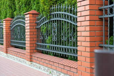 Photo of Beautiful brick fence with iron railing outdoors