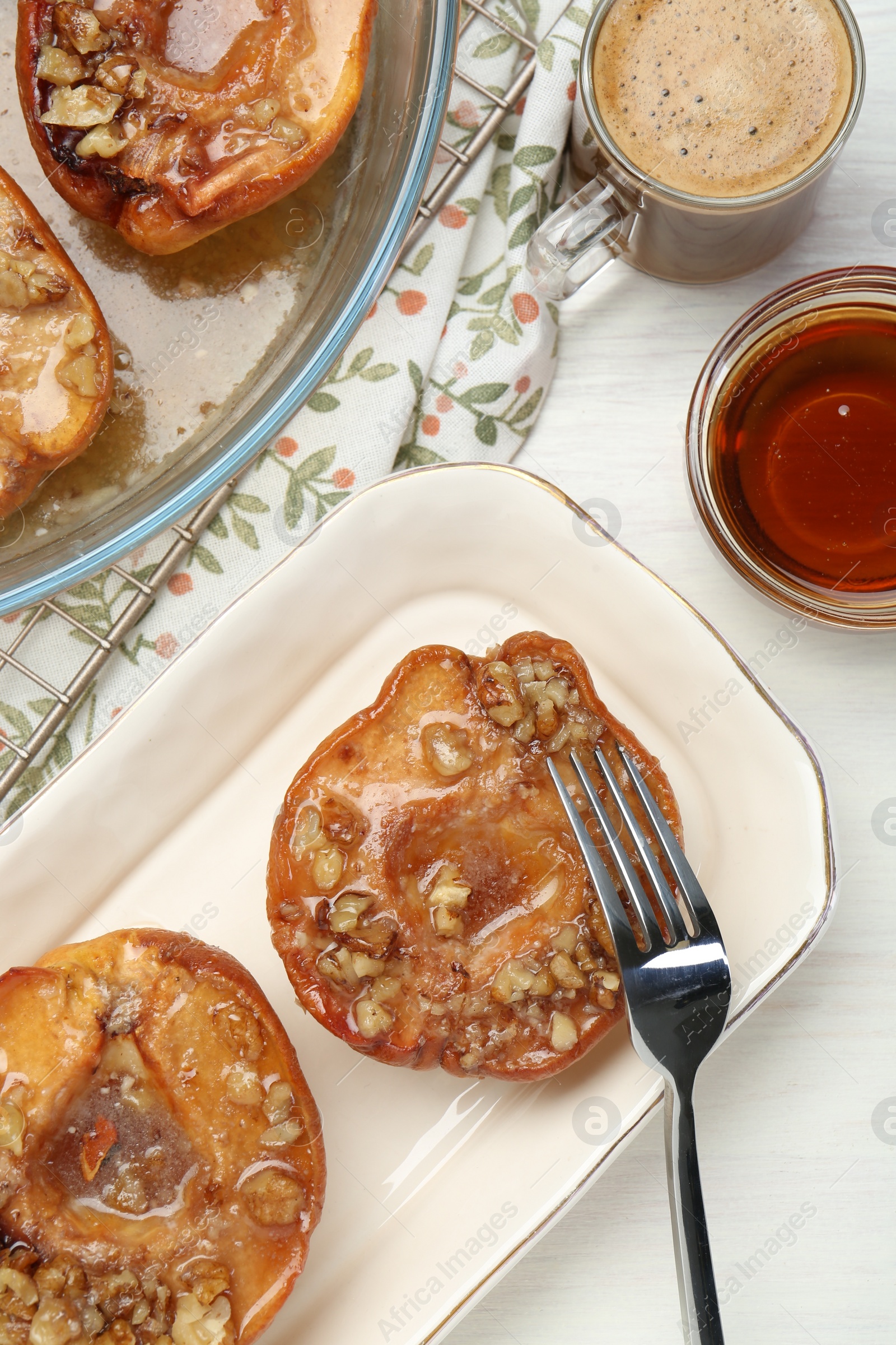 Photo of Delicious quinces baked with honey and walnuts on white wooden table, flat lay