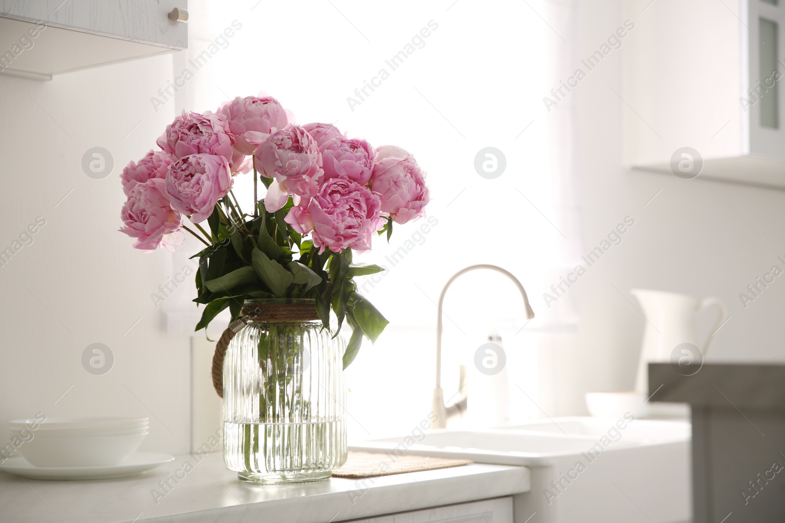 Photo of Vase with bouquet of beautiful pink peonies in kitchen. Space for text