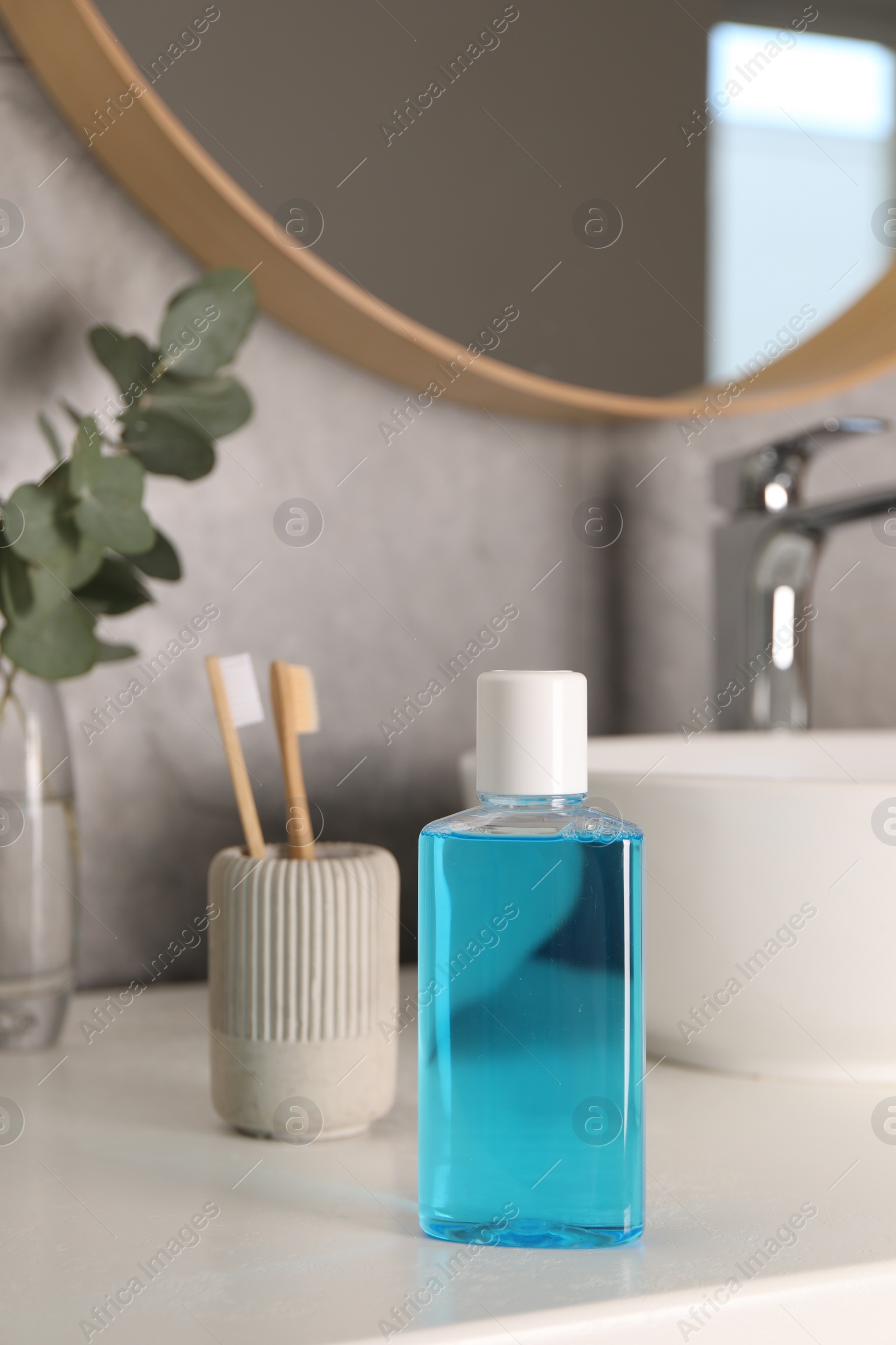 Photo of Bottle of mouthwash and toothbrushes on white countertop in bathroom