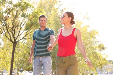 Lovely couple walking together in park on sunny day