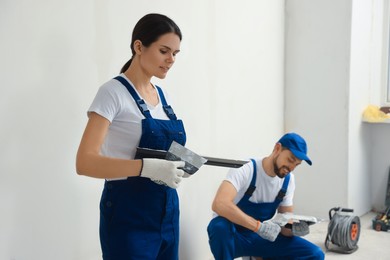 Photo of Professional workers with putty knives near wall indoors
