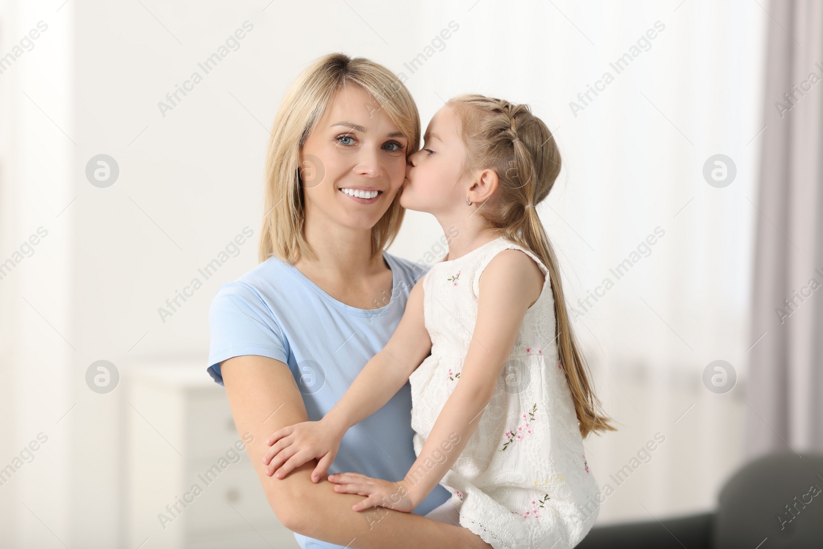 Photo of Daughter kissing her happy mother at home