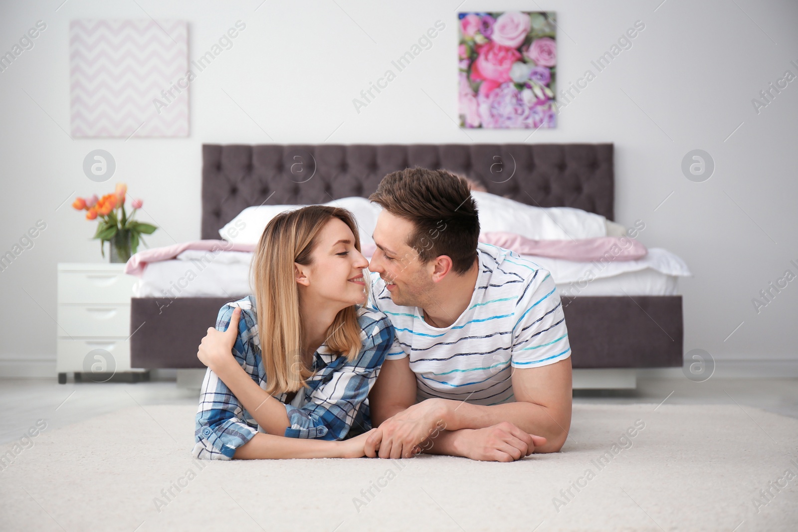 Photo of Lovely young couple lying on cozy carpet at home