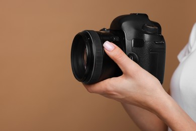 Photo of Photographer with camera on brown background, closeup. Space for text