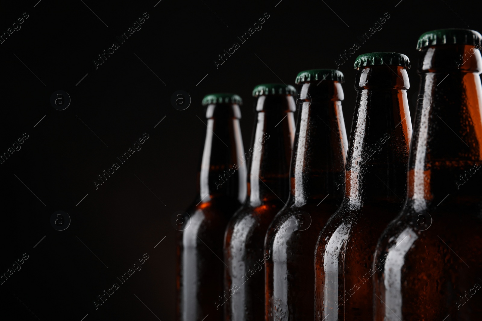 Photo of Many bottles of beer on dark background, closeup. Space for text